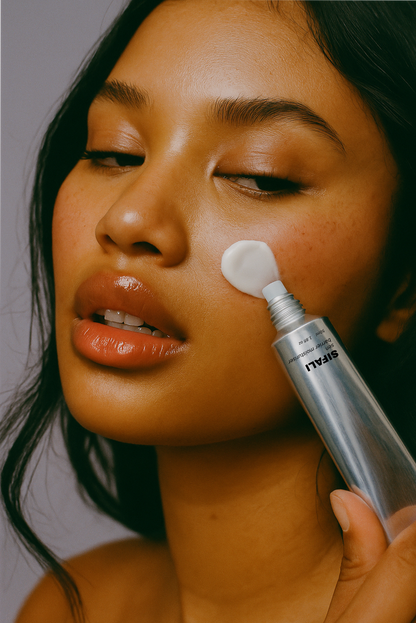Close-up of a woman applying cream to her face with a bottle labeled 'Sifali Sen Barrier Cream'.